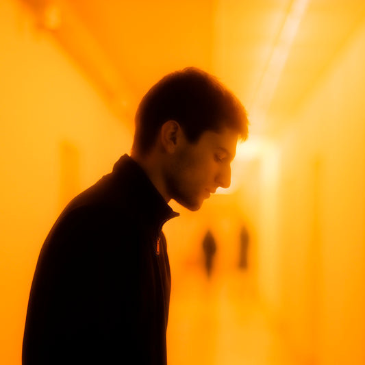 a man standing in a hallway looking down at his cell phone