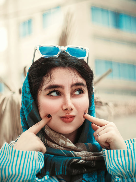 a woman in a scarf and sunglasses poses for a picture