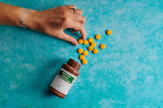 a hand reaching for a bottle of pills on a blue surface