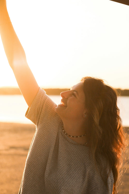 a woman holding up a frisbee on a beach