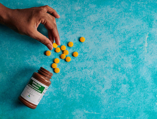 a hand reaching for a bottle of pills on a blue surface