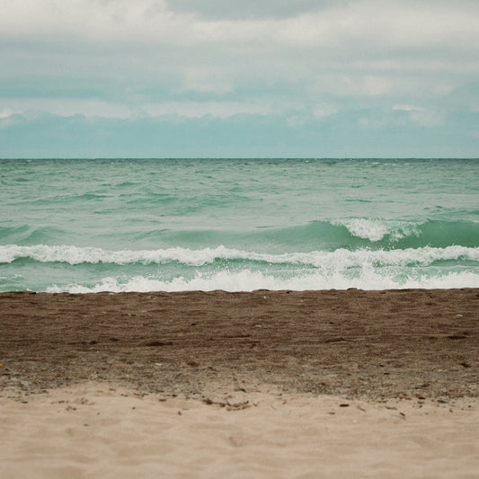 a surfboard is sitting on the sand near the ocean