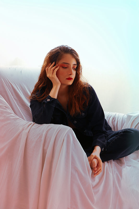 a woman sitting on a couch with her hand on her head