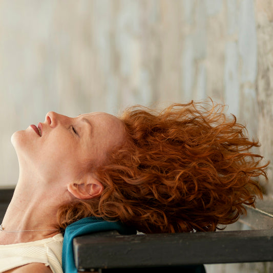 a woman with red hair laying on a bench