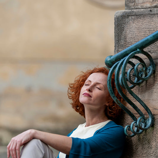 a woman leaning against a wall with her eyes closed