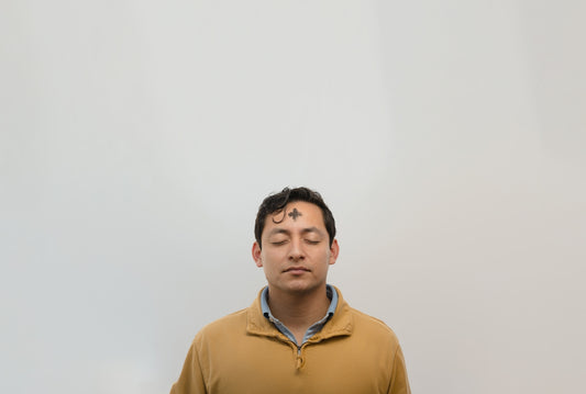 a man with his eyes closed standing in front of a white wall