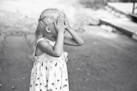 a little girl covering her face with her hands