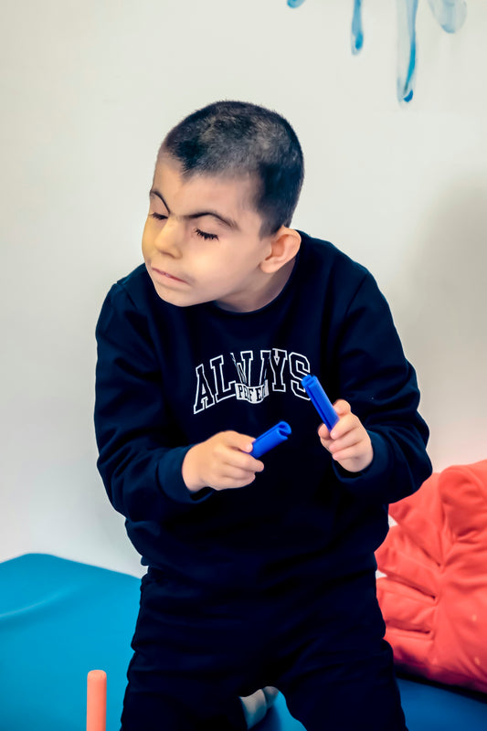 a young boy sitting on a bed holding a toothbrush