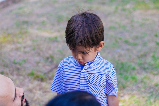 a little boy wearing a blue and white striped shirt