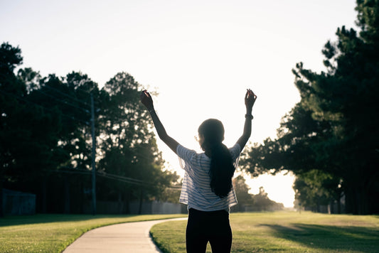 A woman standing on a sidewalk with her arms in the air