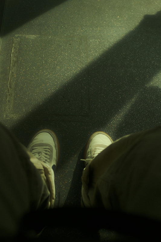 A person standing on a sidewalk with their feet up