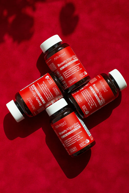 Three bottles of red liquid sitting on top of a red surface
