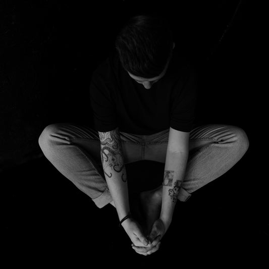 A man sitting on the ground with his hands in his pockets
