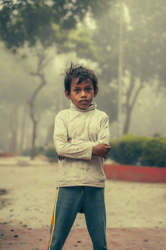 A young boy standing in the rain with his arms crossed