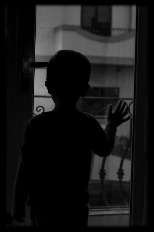 A silhouette of a person standing in front of a window