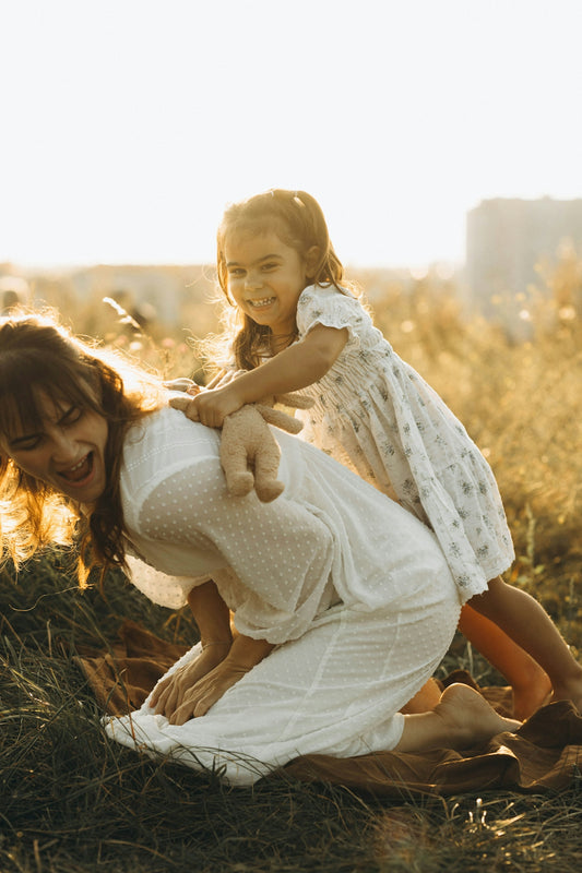 A woman and a little girl playing in a field