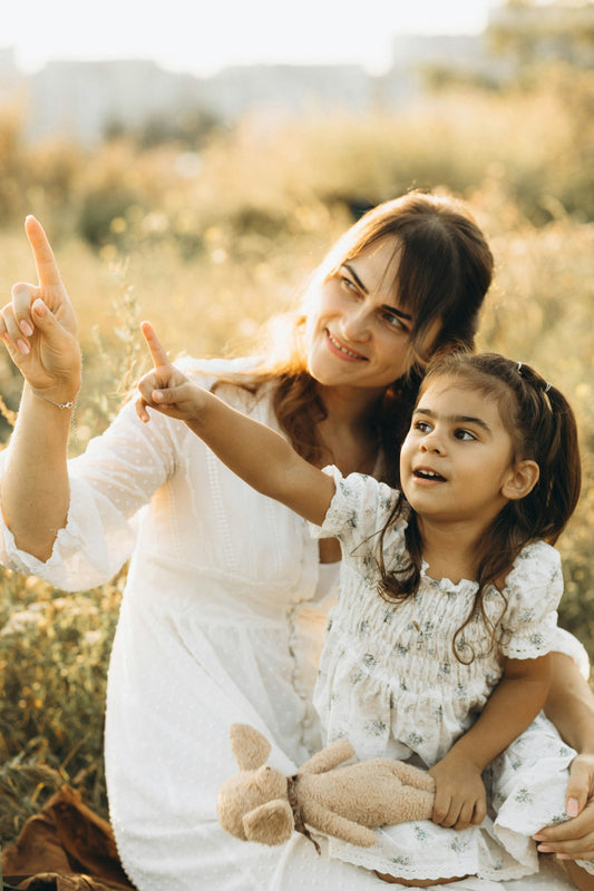 A woman and a little girl sitting in a field