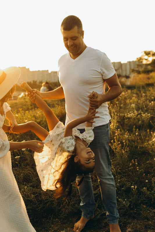 A man and two little girls playing in a field