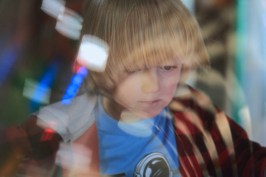 A blurry photo of a young boy looking at his cell phone