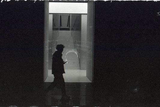 A silhouette walks into a bright opening.