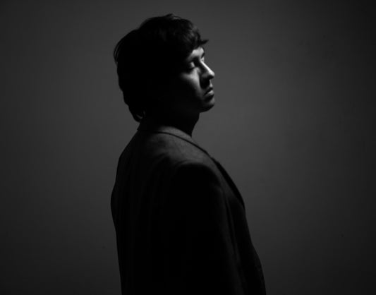 Man in silhouette looks pensively away.