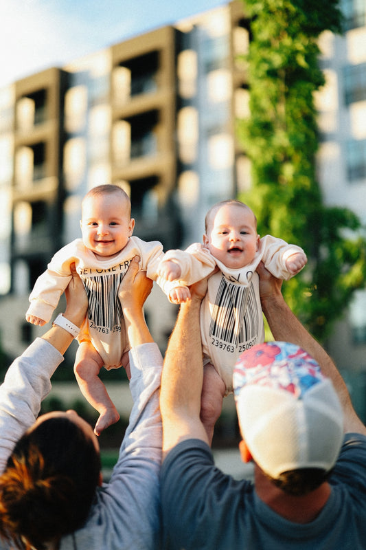Parents are joyfully lifting their adorable twin babies.