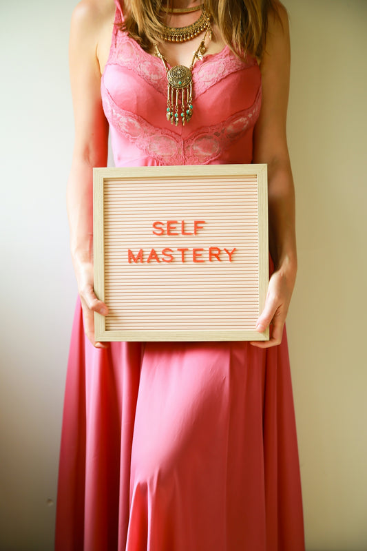Woman holds a sign that says self mastery.