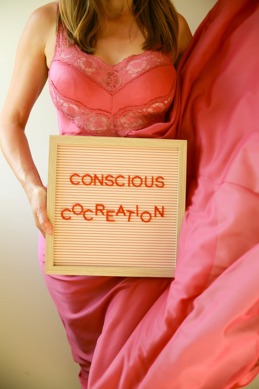 Woman holds a sign that reads conscious cocreation.