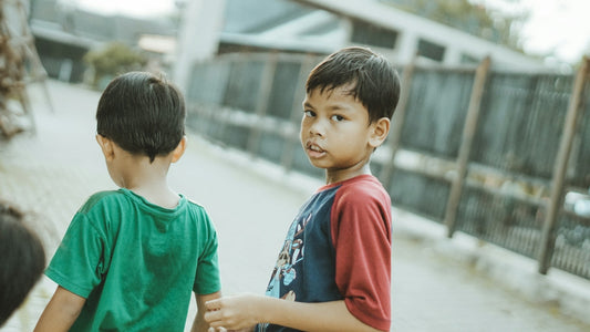 Two young boys walk together in an outdoor setting.