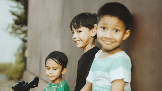 Three smiling young boys pose for a picture.