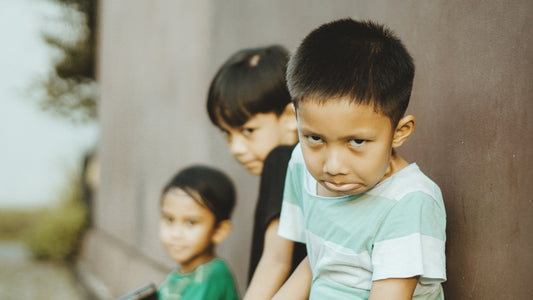 Three young children lean against a wall.