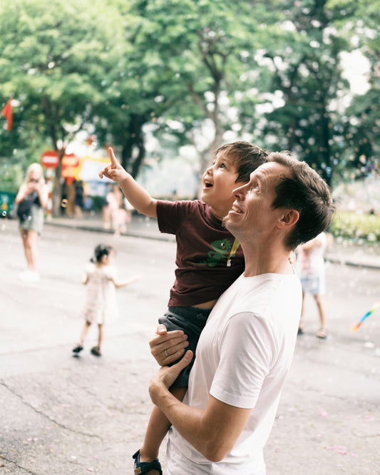 A father holds his son, looking at bubbles.