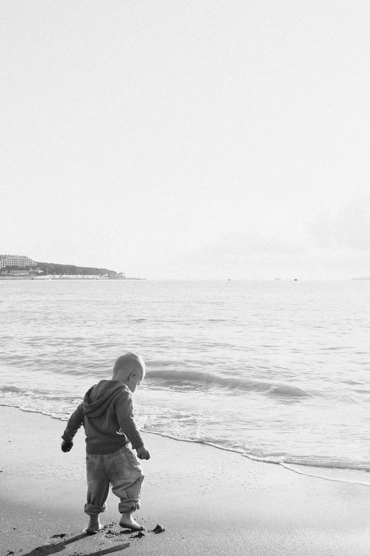 A child plays at the beach, looking outward.