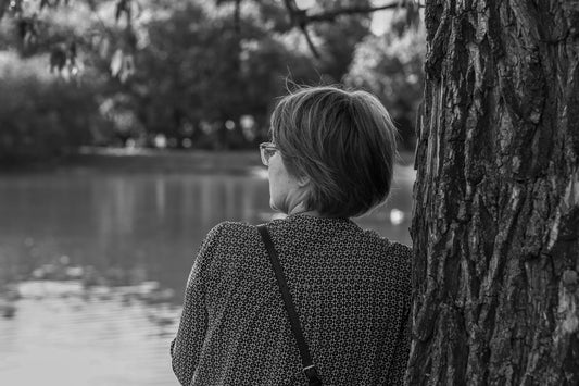 Woman looks out over a lake in black and white.