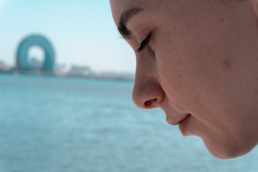 A woman contemplates by the water.