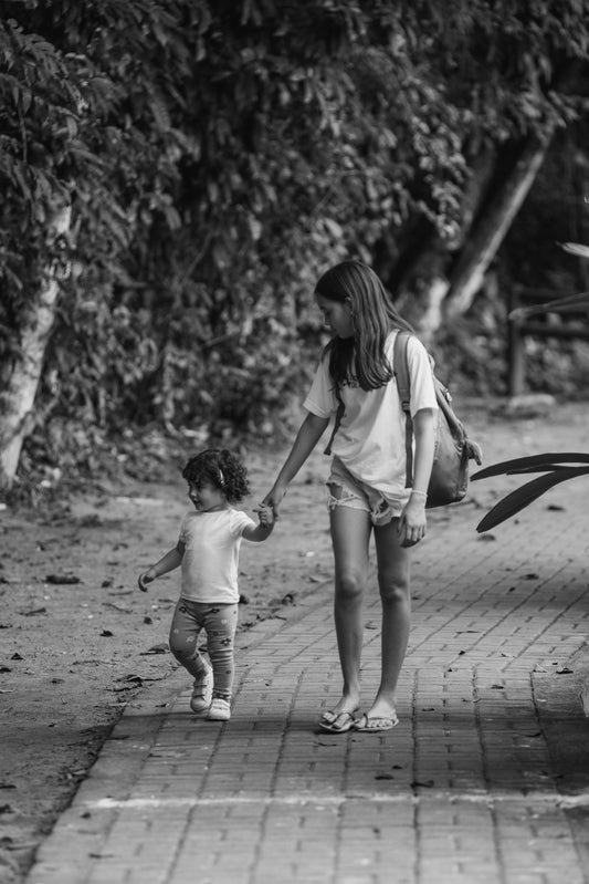 Older sister walks with her younger sibling.