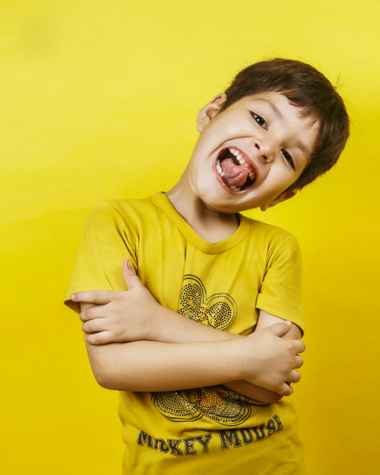 The happy boy grins broadly with his tongue out.