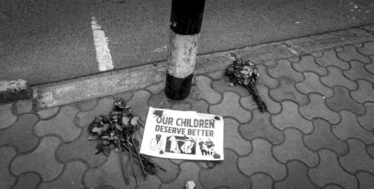 Flowers and a sign mourn for children.