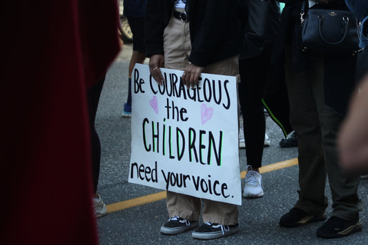 Person holding sign about children needing voice.
