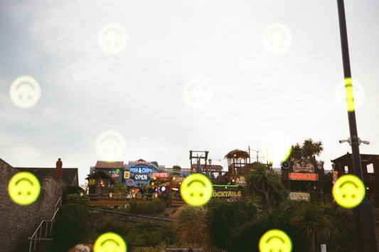 Scattered smiley faces overlay colorful buildings on a hill.