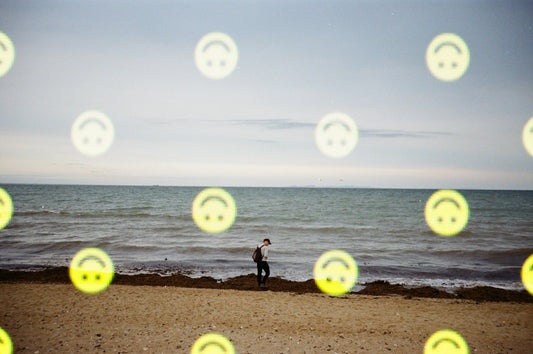 Person walking on beach with smiley faces.
