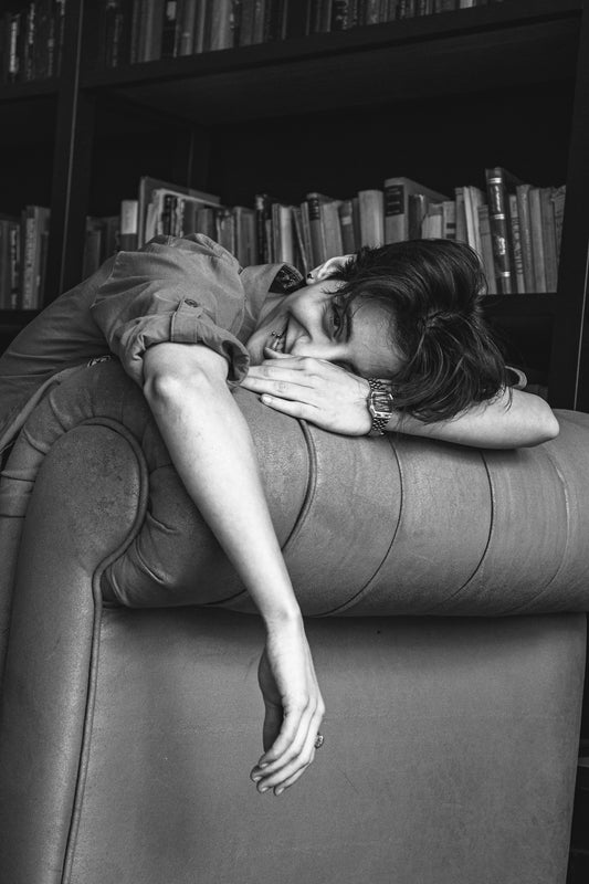 Woman resting her head on a couch armrest.