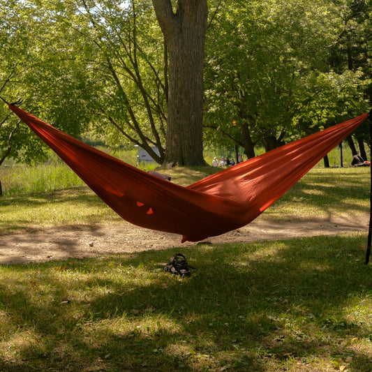 A red hammock strung between trees in a park.