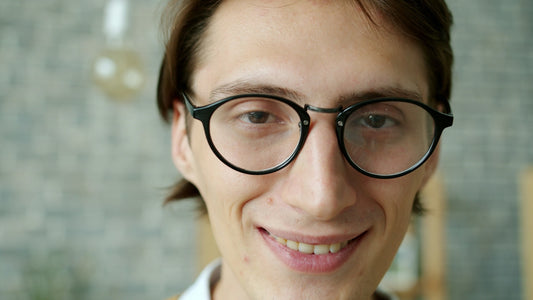 Young man with glasses smiling at the camera.