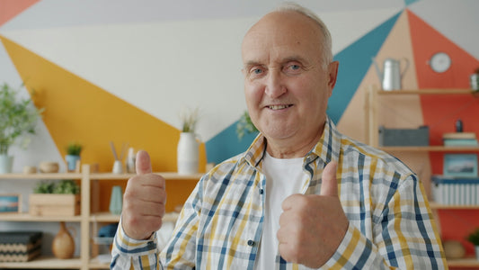 Smiling older man gives two thumbs up