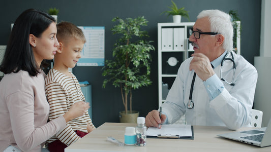 Doctor talking to mother and child at desk.