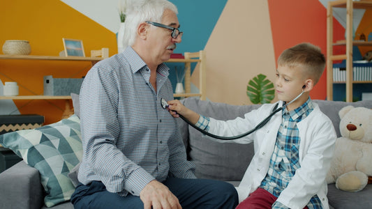 Boy in doctor's coat listens to grandfather's heart