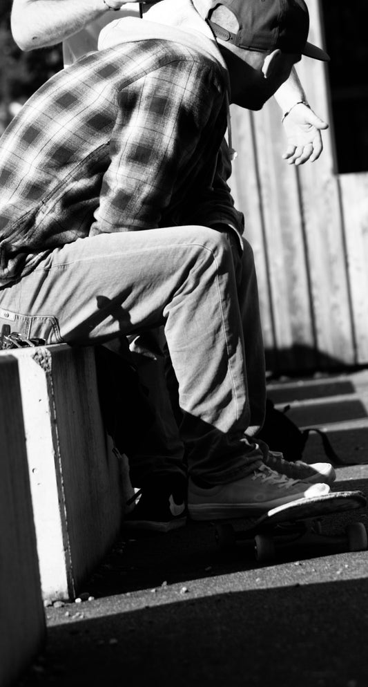 Two people sitting with a skateboard.