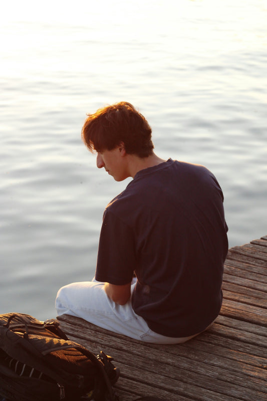 Man sitting on a wooden dock by the water