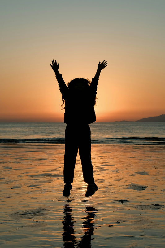 Child jumping on beach at sunset